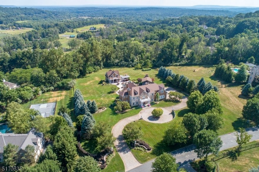 OWN THE PERFECT COMMUTE! Enjoy serene distant views, the soothing sound of a spectacular water feature while walking to an impressive home office.  A separate 2-story structure houses a full kitchen, 2 baths, W/D, stone fireplace wall, custom floating staircase as well as first and second choices for an office location. Working from home was never better, just love the commute! When arriving at the property, an expansive circular paver driveway, lush lawn, dry laid stone walls & mature plantings set the tone. Inside the main home, the two-story foyer & gracious stairway invite the discerning buyer to appreciate the variety of architectural details in ceilings, millwork, hardwood & stone floors. The 16-room home features 5 bedrooms, 3.2 baths, 4 fireplaces, 2 conservatories & office.The walk-out lower level with 10 foot ceilings has myriad possibilities. If you love to entertain & love the outdoors, you will be awed by the outdoor spaces. The heated spa & saltwater pool include a magical grotto complete with waterfall. The pool is flanked by 2 entertainment areas each with its own spectacular kitchen, dining terraces, conversation areas & outdoor tv's. One includes an elegant, covered dining area with chandelier and fireplace. The other has Brazilian Rodizio, keg refrigerator, 2 sinks, 2 refrigerators, fireplace, pergola & is adjacent to the A/C & heated pool house/office.