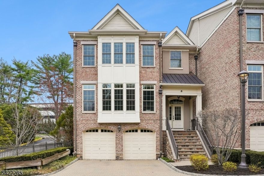 A rare offering in The Brownstones, this sophisticated end-unit townhome captures the timeless appeal of a classic New York-style brownstone in Convent Station. Set in a small, architecturally distinctive enclave with Belgian-block-curb streets, paver driveways, and patios, it offers quality construction, refined finishes, and exceptional flexibility. The location is a true lifestyle advantage, close to the train, Morristown Medical Center, Morris County Golf Club, downtown Morristown, dining, shopping & everyday conveniences. Approx. 4,000 sq ft features 9' and 10' ceilings, hardwood floors, designer lighting & Masonite raised panel doors. The main level includes an inviting foyer, expansive living and dining areas, and an open kitchen/family room with a gas fireplace, an oversized center island, granite counters, stainless steel appliances, a wet bar, a wine fridge, wine storage, and access to a spacious balcony. Upstairs, the primary suite offers a luxurious bath, walk-in closet, and finished attic access, while two additional bedrooms share a generous full bath. The ground level includes a large den, a private office or guest bedroom, a powder room, a covered patio & spacious garage with extra storage. Includes a designed space for a future elevator.Oversized two-car garage with storage and frost-free hose bib. A distinctive home offering elegant, low-maintenance living in one of the area's most convenient settings.