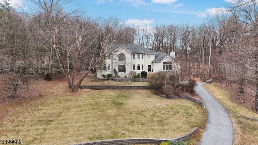 Majestic Custom Estate in Kinnelon, a 6 Beds, 5 Baths with a Massive Finished Basement & In-Law Suite! 45 Alize Drive, a stunning custom home nestled on a private, wooded lot in desirable Kinnelon. This expansive residence offers oversized living areas, sophisticated architectural details, and a flexible floor plan. Enter through grand double doors into a breathtaking two-story foyer featuring polished stone flooring and a sweeping staircase. The main level flows effortlessly into a spectacular Great Room, boasting soaring vaulted ceilings, skylights, gleaming hardwood floors, and a fireplace flanked by a stone hearth. The chef's kitchen is an entertainer's dream, equipped with white cabinetry, stainless steel appliances, dark subway tile backsplash, and a large center island. Host formal gatherings in the elegant dining room, highlighted by a unique circular tray ceiling, crystal chandelier, and large arched windows. Upstairs features generously sized bedrooms, including a luxurious Primary Suite with hardwood floors. The lower level is a true showstopper: a fully finished basement that significantly expands the home's footprint. With a recreation area and a layout functioning essentially as a 7th bedroom, this space is ideal for a potential in-law suite or guest quarters. Exterior features include a stately 3-car garage and a massive rear deck overlooking the serene backyard. Don't miss this exceptional home!