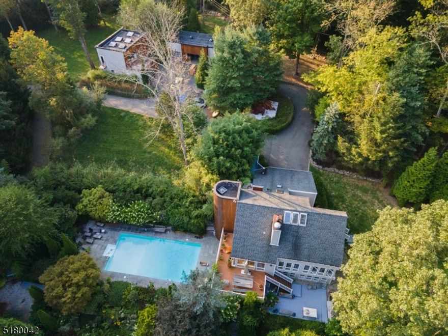 This stunning estate is a "Creative venture to invite inner reflection".  Nestled on 6+ acres, offers a private sanctuary-like setting yet conveniently close to shops, transportation & Mt Olive schools. A winding, tree-lined driveway guides you onto this magnificent property including a main home, 2-story guest home & a detached workshop/garage. Walk the "retreat path" to the flowing stream past the Zen, tiered garden with herbs, vegetables, perennials, & fruit trees that surround the in-ground pool. A perfect blend of modern & rustic designs, the interior of the home features versatile, inspiring spaces. Details include travertine stone, glass tile, wood flrs, beamed ceilings & windows galore inviting natural light & the picturesque landscape indoors. The LR brimming w/sunlight shares a double-sided fireplace w/the 2-story DR & a door to the wrap-around deck overlooking the pool & garden. In the kitchen, quartz & steel counters, wood cabinetry, charming breakfast nook w/doors to a deck. A powder rm, 3000 bottle-wine cellar & access to the attached 2-car garage complete this floor. Unique primary BR suite upstairs w/a fireplace, en-suit bath, vaulted ceiling, skylights, sitting/office area & a huge WIC. Ground level offers addt'l 3BR, laundry, full bath, sauna, FR & access to the pool & expansive gardens. The separate Guest Home features a kitchenette, full BTH, loft/office space, radiant heat, 2 balconies w/automatic industrial doors offering panoramic views of the property