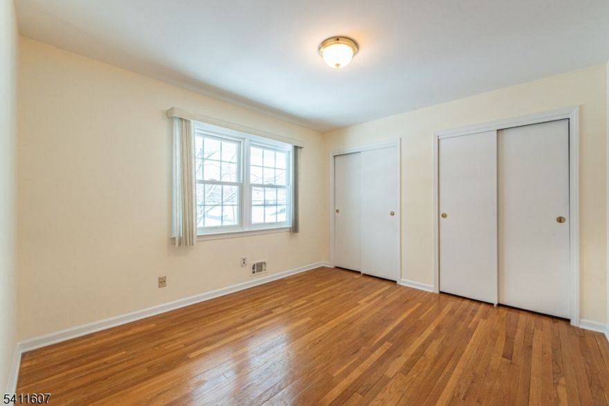 Wow! Welcome to this beautifully maintained 5-bedroom Split Colonial in a desirable neighborhood. Step into the large foyer and into a sun-filled living room with soaring cathedral ceilings, a beautiful bay window, and hardwood floors. The formal dining room with chandelier and high ceilings flows into the eat-in kitchen with white cabinetry and appliances. The majority of the home has been freshly painted and features new plank flooring throughout the ground level, creating a clean, modern feel. The inviting family room offers recessed lighting, a wood-burning brick fireplace, sliding glass doors to the backyard, and convenient garage access. A first-floor bedroom provides flexibility for guests or a home office. Upstairs you'll find four additional bedrooms, including a spacious primary suite with a huge walk-in closet and private bath. The main bath features a double vanity and handicap-accessible shower/tub. Newer windows, including those by Renewal by Andersen, enhance efficiency and style. The unfinished basement offers plenty of storage with utilities. Enjoy the huge, newly fenced backyard with a newer paver patio perfect for entertaining. Located with a park at the end of the street, this move-in ready home checks all the boxes.