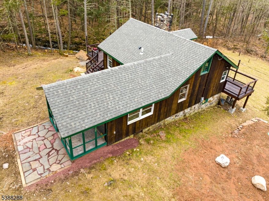 Unplug and unwind in this serene mountain retreat on nearly an acre in Northern NJ where woods, wildlife, and a babbling brook create the ultimate escape. Blending rustic charm with modern conveniences, this 2BR, 1376 sqft custom home is the  perfect setting  for weekend getaways. Oversized deck. This property is a rare opportunity to own your own piece of seclusion.The living room showcases the original oversized hearth fireplace,  exposed beams, and wood floors. Eat in kitchen.  Updates include newer septic, roof, and water conditioner for peace of mind. Easy commute from NYC or neighboring NY or PA locations.