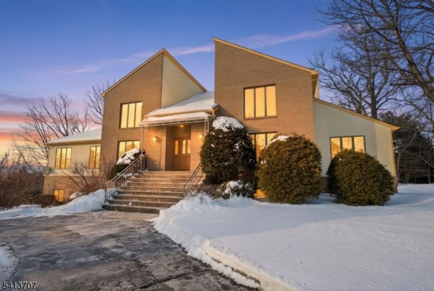 Welcome to 32 Sylvan Drive, an exceptional residence in prestigious Windsor Woods neighborhood. This south-facing property, perched atop a hill, offers unparalleled views and a prime location. This 4,436 sqft home is both comfortable and spacious, featuring five bedrooms and four and a half bathrooms. The open floor plan and large sized rooms provide an ideal setting for modern living. The main level boasts a large eat-in kitchen with sliding doors leading to a deck. A spacious 36-foot living room with a wood-burning fireplace, formal dining room, office space, and additional entertainment areas complete the main floor.This property offers flexible living options with two primary bedrooms, one on the main level and the other on the second floor, each with ensuite baths. The finished walk-out lower level, has separate entrance and bathroom, adding more living versatility. Hardwood floors and marble tiles grace the main and second floors. Main-level laundry further adds to the home's practicality.1 block to Woodmont Elementary School, rated 9/10, easy access to major highways; Routes 46, 80, and 287, and NYC transportation. The property set on a .75 acre lot features a circular driveway and three-car garage, with plenty of storage. The south-facing orientation ensures abundant natural light and breathtaking sunset views. Montville Township is renowned for its prime location, offering a harmonious blend of suburban tranquility and urban accessibility.