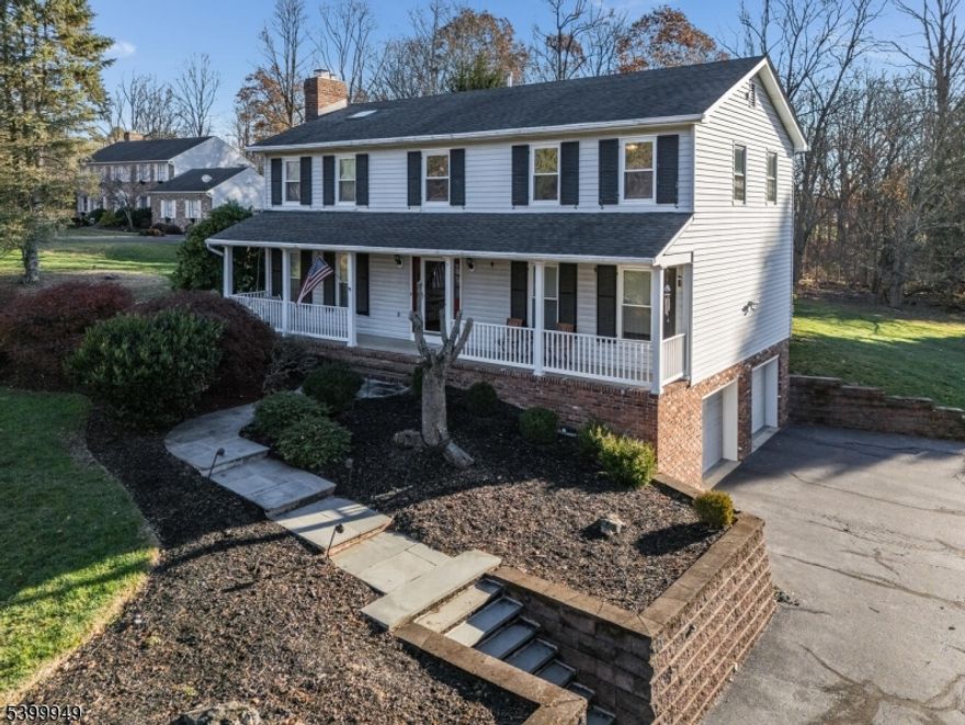 Classic Colonial-style home, featuring four bedrooms and two and a half bathrooms. Situated on a well-landscaped 2.12-acre deep lot, the property offers a charming front porch and is conveniently located just two minutes from Route 78, shopping and restaurants. The interior boasts an updated kitchen with granite countertops, stainless steel appliances, new microwave and dishwasher, freshly finished wood cabinetry, decorative tile backsplash, and a convenient pantry for storage. Warm hardwood floors are featured throughout the home.  A floor-to-ceiling brick wood burning fireplace graces the family room creating a cozy atmosphere on a chilly night. The primary bedroom suite with a cathedral ceiling, skylight, large walk-in closet, granite counter vanity with dual sinks, and updated tiled shower. Other features include an updated hall bath and spacious secondary bedrooms. The Trex decking overlooks the spacious landscape offering a lush tree buffer. Newer windows, AC condenser, a salt-free water softener system, and insulated garage doors. The garage features additional storage. This home is set in a delightful neighborhood setting.