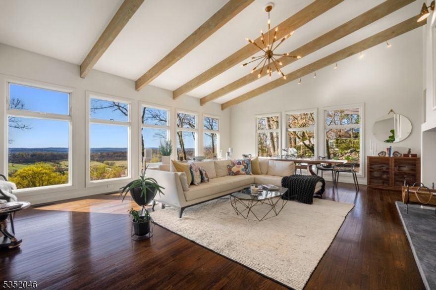 This architecturally striking California-style ranch, crowned with an iconic butterfly roof, seamlessly integrates mid-century modern and contemporary influences, creating a one-of-a-kind haven designed to embrace the breathtaking VIEWS. Inside, the foyer opens to a dramatic great room, with soaring ceilings, exposed beams, and an expansive wall of glass showcasing a gorgeous panorama. A sleek glass railing overlooks the sculptural staircase, accented by a bold tiger-striped runner. The professionally designed chef's kitchen features custom NEFF cabinetry in olive wood and black matte metallic, a 10-foot island, a Sub-Zero refrigerator, side-by-side Viking ovens, a full wall pantry, and an oversized glass window framing the lush landscape. The adjacent living area connects seamlessly to both upper and lower patios, ideal for entertaining. The primary suite is a luxurious sanctuary with hardwood flooring, a spa-inspired bath with heated floors, dual floating vanities, a freestanding Bain Ultra jetted tub, and an expansive custom closet. This level includes two additional bedrooms, a sophisticated hall bath, and laundry room. A spacious lower-level family room with wet bar opens to terrace views, while a gym, private guest suite, and steam bath complete the space. Additional highlights include a bluestone entry, hardwood and polished concrete floors, 4-bed septic ('24), whole-house generator, Sonos system, dual-zone Trane HVAC, and new irrigation system.