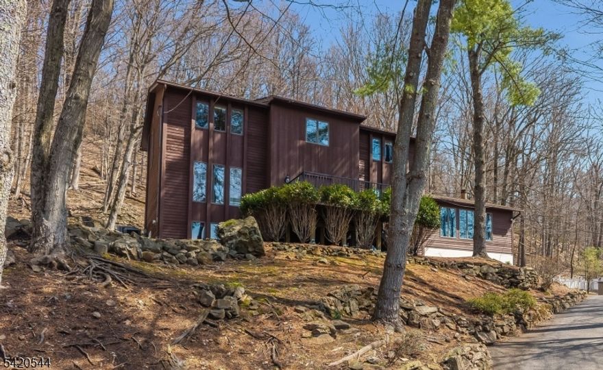 Stunning contemporary in a gorgeous natural setting, with tastefully renovated kitchen and bathrooms. Featuring a center island with seating, stainless steel appliances, glass backsplash, maple cabinets and granite, the kitchen is a delightful space filled with natural light with french doors leading to a serene deck and stone garden. Large rooms provide ample space for entertaining. The family room is anchored by a dramatic volcanic rock fireplace, soaring vaulted ceiling, and tall windows with abundant natural views. A unique open porch at the front entry provides relaxing outdoor space overlooking wooded sunsets. Primary suite is a spacious retreat with a spa-like renovated bathroom enhanced by radiant-heated floor double vanity, and luxurious walk-in shower floored with river stone. The basement is finished as a guest/in-law suite, with a recreation room, full bathroom, dining nook, and large bedroom. The expansive back deck is perfect for outdoor entertaining and enjoyment: an oasis surrounded by mature woods and historical stone walls. Don't miss this exceptional home located on one of Bridgewater's loveliest streets.