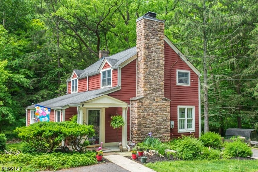 A storybook setting for this enchanting 3-bedroom home boasting 3 levels of living space nestled on a tree-lined lot with stream in the historic Stephensburg section of Washington Twp.  A covered front porch leads you into a charming sitting room-office overlooking the living room with impressive, floor to ceiling, raised hearth wood burning fireplace with stone surround and built-in bookcases on either side. The dining room with wainscoting has sliding doors that open onto an expansive deck to enjoy your morning coffee to the soothing sounds of Stephensburg Creek. The updated eat in kitchen features granite counters, subway tile backsplash, stainless appliances, recessed lights & pantry. Wood floors in all the bedrooms (under carpet in the primary BR). Updated full bathroom with granite topped vanity, linen closet and tub/shower. The walk-out basement offers additional living space with carpeted floor, pellet stove, unique stone bay windows, built-in window seat, half bath, laundry area, and utility/storage closets. Fabulous nearly 2-acre property with stream, stone walls, and flower beds. Just enough privacy between neighbors and front & back view to woods. Automatic propane generator for peace of mind. Top-rated West Morris Schools. Minutes to Mansfield shopping: Walmart, Kohls, Shoprite, theater, local farms, craft breweries and restaurants. Ready for new owners to bring their loving touch and continue the history of this appealing home and property.