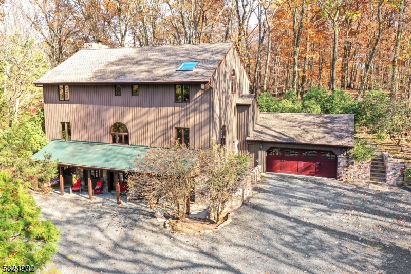 Discover this extraordinary bank house tucked away on just under 3 private wooded acres. This unique residence showcases the perfect blend of natural beauty and sophisticated design. The heart of this home features a chef's kitchen that would make any culinary enthusiast smile, while the family room boasts a dramatic floor-to-ceiling stone fireplace that serves as both a focal point and gathering space. The dining room, embraced by three walls of windows, offers breathtaking views of the spectacular redwood deck and natural stone patio, creating an enchanting indoor-outdoor living experience. With three to four bedrooms and three full bathrooms, this home perfectly balances intimate spaces with entertainment areas. The two-floor primary bedroom suite offers a luxurious retreat, complete with a dressing room and private balcony - your personal sanctuary above it all. Exterior features include beautiful landscaping with artfully crafted stone walls. As a bonus, with no grass on the property, lawn mowing is not required! An oversized two-car garage provides ample parking and storage, while the paver and stone circular driveway leads to a welcoming covered front porch. This meticulously maintained home represents the perfect escape from the ordinary, where nature and luxury unite to create an exceptional living experience. Ready to make this distinctive property your own?