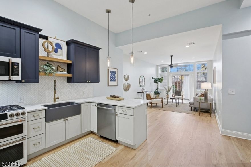 Modern living abounds in this newly renovated, sun drenched, first floor, loft style condo. An open floorplan coupled with exceptionally high ceilings, large windows allowing in extraordinary light, and freshly refinished oak flooring throughout gives this special unit an impressive feeling of light and spaciousness. The kitchen has been reimagined with a stunning marble backsplash set in a sophisticated herringbone pattern, new quartz countertops, and a suite of matte white GE Cafe appliances with brushed bronze hardware. Opening out from the kitchen breakfast bar, the living/dining area is open and welcoming to simple relaxation or robust entertaining. Two large bedrooms flank the luxurious main bath with marble tile floor and walls, and a walk-in shower tiled in gorgeous marine blue ceramic tile with brass rain head shower and handheld wand. The extra-large primary bedroom has a special reading nook and two large, fully customized walk-in closets. Second bedroom is also large with its own customized closet and soaring ceilings. Central air conditioning. Laundry in unit. Two assigned parking spots in dedicated lot. Convenient to Bloomfield Center, Montclair, Montclair State University, GSP and more. Pets welcome.