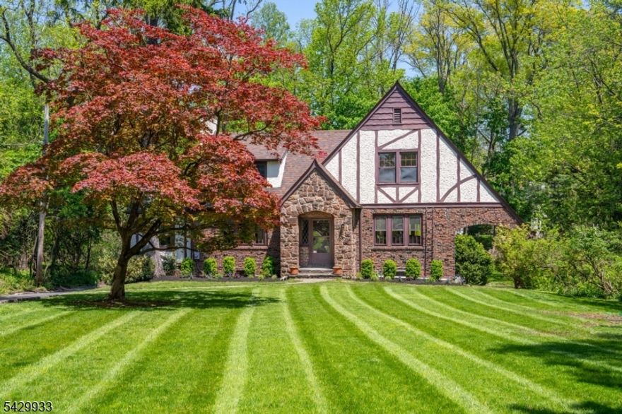 Don't miss this rare opportunity--first time on the market in over 30 years. This timeless Tudor blends classic elegance with modern luxury and is set on a stunning 0.52-acre lot with a large yard and lovely landscaping. Set back approximately 150 feet from the road, the home offers added privacy, helps minimize road noise, and maintains exceptional curb appeal. Inside, classic Tudor charm meets thoughtful modern updates. A spacious foyer welcomes you into bright, refined living spaces with tasteful finishes and a seamless flow. The living room opens to a sun-filled family room with lovely wooded views and access to a large deck, perfect for relaxing or entertaining. A flexible room can serve as a bedroom, office, or guest room. The formal dining room leads to a stylish custom kitchen with a built-in laundry closet. A powder room tucked behind the stairs adds convenience to the main level. Upstairs, the primary bedroom offers ample closet space, a sitting area, front and backyard views, and a private en-suite bathroom. Two additional generously sized bedrooms share a full bathroom. The basement provides extra space for storage, a home gym, or recreation. A large two-car garage connects to the backyard, with additional parking for multiple cars. Ideally located just minutes from Short Hills and Millburn train stations, highly rated assigned public schools, and renowned private schools including The Pingry School and Far Brook School.