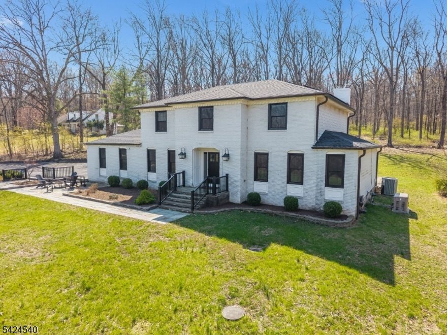 Set on a picturesque, tree-lined 3-acre property, this custom Colonial blends timeless craftsmanship with modern upgrades and thoughtful design throughout. From the moment you enter, you'll notice the detailed moldings, elegant wainscoting, hardwood flooring, and custom built-ins that give the home its refined character. The heart of the home is a beautifully designed custom kitchen with a bright breakfast area and access to a covered deck perfect for morning coffee or entertaining. Step outside to a bluestone patio that extends your living space into the serene backyard. Inside, the spacious family room with a wood-burning fireplace creates a warm and inviting setting. Upstairs, you'll find four generously sized bedrooms, including a luxurious primary suite featuring hardwood floors, dual vanities, heated floor, steam shower, & custom cabinetry. A unique adjoining fourth bedroom offers flexibility as a private office, dressing room. The second floor also includes a convenient second laundry room and an updated hall bath. The finished basement adds exceptional versatility with a large living area, kitchenette, additional laundry room, and abundant storage - ideal for guests, recreation or just extra living space. This home is equipped for modern living with debt-free solar power, an EV charger, and a whole-house generator. A detached garage/workshop with a wood stove provides additional space for hobbies or storage, while copper gutters add a distinctive finishing touch