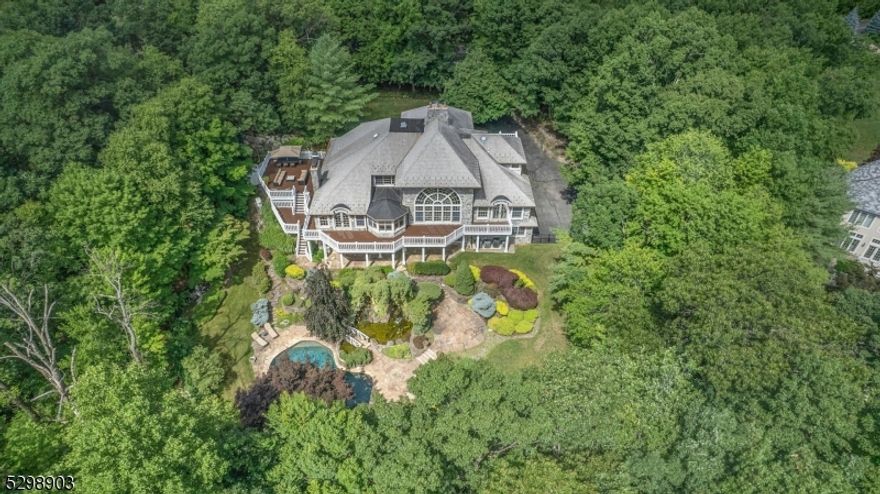 Are you a connoisseur of life? Custom-built by the owners in 2010, this lakefront labor of love was thoughtfully designed for living life to the fullest. Just 40 miles from NYC and discretely nestled on 1.45 acres in the gated lake club community of Smoke Rise, the 5 bdrm, 4.5 bth retreat offers nearly 8,000 sq.ft. of luxury on 3 levels with an elevator, 4-car garage, serene gardens, pond and waterfalls, inviting saltwater pool, and scenic lake views. Architecturally stunning, it features a granite block exterior with spectacular custom Anderson windows, arched antique front doors, heated slate look roof, and massive 2-level wraparound deck. Notice distinctive details like the dramatic curved staircase with hand-carved newel post, inlaid hardwood floors, and antique chandeliers. The living room showcases a soaring cathedral ceiling, antique marble French fireplace, and breathtaking Palladian window with lake views. The gourmet kitchen includes 2 oversized islands, separate Sub-Zero fridge and freezer, Wolf oven and Viking gas range. The expansive 1st-floor primary suite offers beautiful views, 2 walk-in closets and a spa-like onyx bath. On the walk-out lower level, a spacious 5th bedroom and full bath offer potential for an in-law suite. For wine connoisseurs, the home's impressive wine cellar features granite walls, an antique brick floor, and 200 yr-old stained glass window. There's also a gym, 2 family rooms, 3 fireplaces, 2 laundry rooms, security system, and generator.