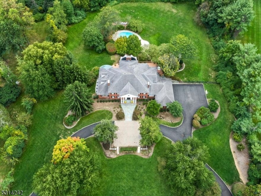 EXTRAORDINARY GEORGIAN COLONIAL - This stunning brick estate home, located in Harding's New Vernon section, sits on a quiet cul-de-sac just 5 miles from Morristown and 30 miles from NYC. The lushly landscaped property features a heated pool, stone patios, numerous outdoor entertaining areas, flat lawns and a circular driveway with ample guest parking. Richly detailed rooms feature custom architectural elements like inlaid floors, layered moldings and exquisite marble. The updated kitchen has a large island, a light-filled dining area, an adjacent butler's pantry and access to the spacious covered terrace overlooking the private backyard. The first-floor primary suite features two walk-in closets and two full bathrooms. Four additional large bedrooms, each with their own full bath, are located on the second floor. The luxuriously finished walkout lower level hosts an incredible entertainment space with handsome bar, a stunning THX movie theatre and a temperature-controlled wine cellar. It also houses an exercise room, steam and sauna, a bedroom, full bath and kitchen.
