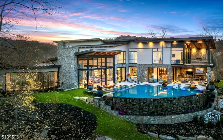 An Aspen, Colorado home on the East Coast? This Modern Day Glasshouse designed by Colorado-based firm, Berglund Architects, sits on an 8-acre private peninsula surrounded by water. Located in the Prestigious Smoke Rise community just 35 minutes from NYC, your serene & peaceful escape awaits. This Private Peninsula Estate features 10,321 square feet of finished living space including 6 bedrooms (2 primary suites), 9 baths, a finished basement lounge, and an 8-car garage with plenty of room for all your off-roading toys. The minute you walk in the front door you will be captivated by floor-to-ceiling windows overlooking a setting that cannot be duplicated. A world-class infiniti pool & spa overlooking Lake Kinnelon, an incredible full outdoor kitchen and fireplace, & a designer tailor-made bar drum-up the most tranquil outdoor backdrop you will ever see. Built in 2022 with a vision in mind for years to come!