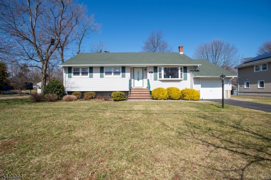Situated on a desirable, sprawling  lot, this beautifully updated Ranch home features freshly painted sunlit interiors, timeless charm, and thoughtful upgrades throughout! A paver stone walkway leads to classic brick steps and a front door with decorative glass inlay. Gorgeous hardwood floors flow seamlessly from the living room into the dining area, which overlooks the backyard. The living room is bright and inviting, with a large bay window and an electric fireplace framed by a richly detailed wood surround and mantle. The eat-in kitchen boasts handsome cabinetry, a sink beneath a window, overhead lighting, gas range, dishwasher, brand-new stainless steel refrigerator, ceiling fan with light, and durable laminate wood flooring that can also be found in the versatile bonus room. All three bedrooms feature hardwood floors, ceiling fans with lights, ample closets, and multiple windows. The full bath includes a lovely pedestal sink, roomy shower, and linen closet. A spacious unfinished basement with washer/dryer and windows offers a flexible space for storage, a workshop, or eventual finishing. The backyard, bordered by a white fence and complete with a storage shed, provides room for recreation, gardening, or relaxation. This property is located close to NYC trains/buses, restaurants, shopping, Rutger's University and RWJ  hospital.  *** Please note only 1 shed will remain on the property***