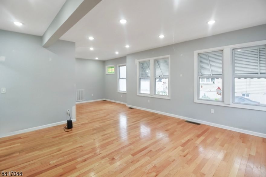 Beautifully renovated first-floor unit offering modern finishes and generous living space with the added bonus of a fully finished basement. The main level features a bright open-concept layout connecting the living room, dining area, and kitchen, perfect for both everyday living and entertaining. This level includes two spacious bedrooms and two full bathrooms, including a primary bedroom with its own private bath. Hardwood floors, recessed lighting, and updated fixtures throughout create a clean, contemporary feel. The finished basement significantly expands the living space with a large recreation room, a versatile bonus room ideal for a home office, gym, an additional bathroom, and laundry hookups. Outside, the property offers a private backyard area along with a detached garage and additional parking. Conveniently located near major highways, shopping, restaurants, and public transportation, making commuting to NYC quick and easy.