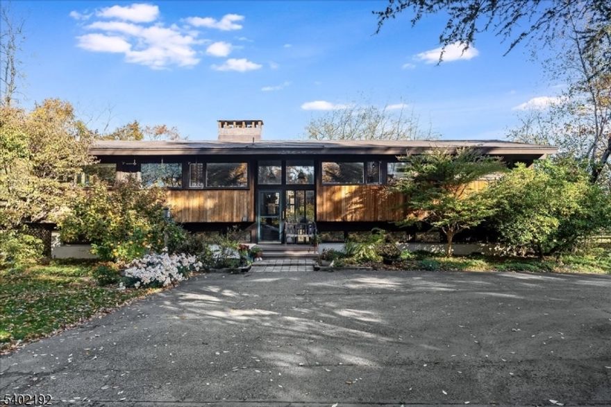 Held by the same owner for nearly five decades, this custom mid-century modern home, known as "Sachem Ridge,  is privately set along a picturesque country road in desirable Tewksbury Township. Positioned toward the back and well off the road on 3.21 acres, the home offers exceptional privacy while embracing natural light and elevated views. The main living level features vaulted ceilings, clean architectural lines, and an open layout ideal for everyday living and entertaining.The home offers 4 bedrooms and 3 full baths, plus two additional flexible rooms perfect for guest space, a home office, or gym. Two brick fireplaces anchor both levels, adding warmth and character, with a wood-burning insert on the first floor and a traditional wood-burning fireplace on the second. Newly refinished hardwood floors, fresh interior paint, and updated baths create a bright, turnkey feel.Outdoor living is equally compelling with a screened porch overlooking wooded grounds, a kidney-shaped concrete in-ground pool, tranquil koi pond, and level lawn. A detached two-car garage includes a walk-up unfinished loft with balcony overlooking the pool, offering exceptional potential.A custom mid-century modern home set naturally within its wooded surroundings, defined by privacy, light, and enduring design.