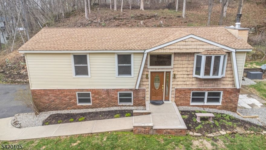 Tucked away at the end of a quiet road, this well-maintained 3-bedroom, 2-bath bi-level offers a peaceful rural setting on just over 2 private acres. Surrounded by nature, the property is within walking distance to the Paulinskill River, with the Kittatinny State Trail running along the rear. The home is move-in ready and features a comfortable living room with a wood-burning stove insert. Recent updates include newer bathrooms, new luxury vinyl flooring, and an updated white country kitchen with granite countertops and modern appliances. A bright sunroom provides scenic views and access to an expansive deck, ideal for relaxing or entertaining. Outdoor elevator adds handicap accessibility. Additional features include a spacious 2-car garage and storage shed.