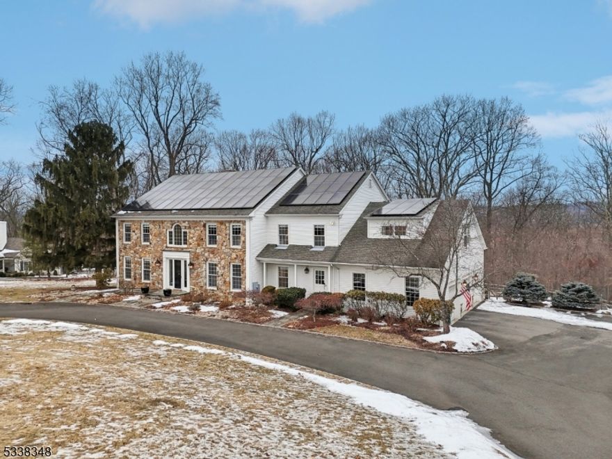 Set on over 3 acres on top of Gladstone's Sheep Hill, this sprawling stone-front Colonial delivers an unmatched blend of elegance and tranquility. An impressive circular driveway leads to this 5 bedroom, 4 full and 3 half bath home with an exceptional floor plan perfect for today's lifestyle.  The exquisite family room with fireplace boasts two stories of incredible windows that fill the home with natural light throughout. Even the most discerning chef will enjoy the recently renovated custom kitchen, fit with Jenn-Air appliances and oversized subzero wine refrigerator. The first floor is complete with a large formal dining room, living room, home office with fireplace, 2 powder rooms, laundry room and 3-car garage. Upstairs, the oversized primary suite is the perfect retreat with large en suite and 2 walk-in closets. Four additional bedrooms finish the second floor, two with en suites, and the other two bedrooms joined by a full bath. The massive finished basement with half bath lends itself to a multitude of possibilities; whether a home gym, media room, or playroom is among your must-haves, there is no shortage of space for customization. With endless wooded views and a park-like property suited for recreation and relaxation, this home has it all! The Solar panels have been paid and are yours to enjoy the benefit that solar brings.