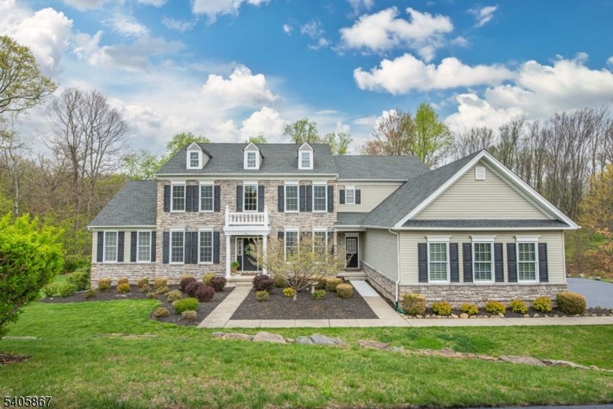 Impressive 5 BR, 4.1 BA Toll Brothers stone-front Colonial in prestigious Morris Hunt in Flanders offers 1.62 acres and approx. 4,368 SF above grade living plus 1,400 SF in a beautifully finished & permitted walkout lower level. A grand 2-story foyer w/sweeping staircase, rich hardwood flooring & elegant millwork sets the tone. Formal LR & DR showcase refined crown & chair rail molding. The gourmet EIK is designed for both everyday living & entertaining, featuring custom wood cabinetry, granite center island w/ gas cooktop, SS appliances, recessed lighting, 2nd staircase & sunlit breakfast area w/ French doors to the yard. The inviting FR offers architectural columns & a striking stone gas fireplace. Private 1st floor office w/ bay window & custom built-ins, powder room, laundry & mudroom w/ separate entrance. Highly desirable and rare 1st floor in-law suite provides exceptional flexibility w/ BR, den, WIC, full bath & separate HVAC. Upstairs, the luxurious primary suite is a true retreat w/ sitting room, dual WICs & spa-like bath w/ jetted tub, shower & double vanity. Princess suite w/ private bath plus 2 additional BRs w/ Jack & Jill bath. The finished walkout lower level is ideal for entertaining & recreation, complete w/ home theater, sound system, flexible studio/office space & storage. Enjoy a private backyard oasis w/ open & wooded views, offering a peaceful setting & beautiful seasonal scenery. Truly a magnificent dream home!