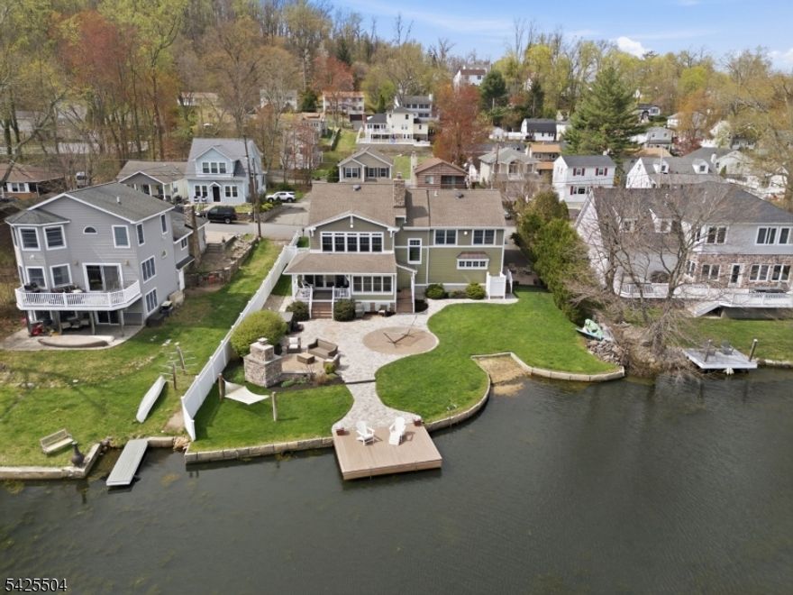 Absolutely stunning lakefront Craftsman style Colonial on one of the most desirable & few double lots on Indian Lake, offering panoramic water views & timeless design. 6 BDRM / 3.5 BATH TOTAL. Open concept main level with hand scraped HW floors, a striking stone fireplace & a sunroom with cedar plank-style ceiling extending the living space with full lake views. Classic kitchen with granite, shaker cabinetry, SS appliances & walk-in pantry. Dining room with double sliders seamlessly connects to the outdoors, perfect for Summer entertaining. Incredible family room currently set as a pub style room with coffered wood ceilings, stone wall facade, raised booth seating & full wet bar. Upstairs features 5 bdrms & 2 full baths, including a primary suite with high ceilings & 2 walk in closets. The walk up attic offers expansion potential. Smart recent updates include french drains & natural gas generator which adds peace of mind. Resort style exterior with private beach, dock, patio, fireplace, hot tub, outdoor shower & lawn for games & relaxation. Fenced in for privacy. Bonus 1BR/1BA apartment over 2 car garage with private entrance, parking & meters ideal for guests or rental income. Enjoy everything the ILCC community has to offer, including a clubhouse, 3 beaches & motorboat friendly waters. With year round activities for all ages, from boating, swimming & fishing to ice skating, this is more than a home, it's a lifestyle. Minutes to DWTN Denville, NYC transit & major highways.