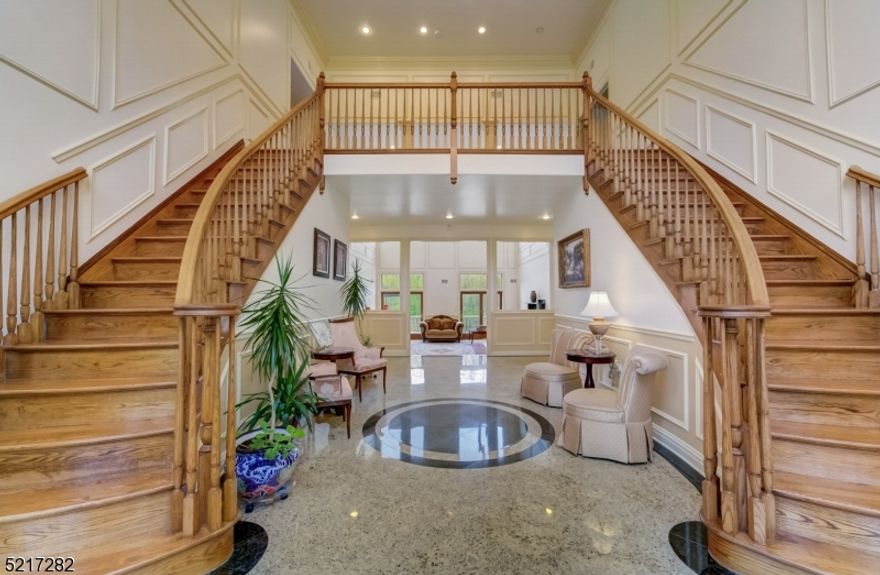 A NE facing home within a highly sought-after community, this fully brick residence exudes sophistication from the moment you step onto its granite steps w/ balustrade rise. The grand entryway welcomes you with a sweeping double oak staircase & the interior spaces seamlessly blend together, forming a harmonious flow that is perfect for both entertaining & everyday living. The 900+ sq ft gourmet kitchen serves as the heart of the home, complete with top-of-the-line appliances, custom Brazilian wood cabinetry, & a generously sized U-shaped center island perfect for culinary creativity. The main floor includes an en-suite bedroom w/ a full bath and WIC, laundry room, & a powder room. The primary suite at the top of the staircase is a private sanctuary that exudes serenity & indulgence, featuring two large dressing rooms & a luxurious en-suite bathroom complete w/ double sinks, a jetted tub, & a spacious walk-in shower. The remaining 4 bedrooms are en-suites, each unique in size and style, offering comfort and privacy.  Newly finished 3,000 + sq ft lower level boasts of marble tiles, a large-scale kitchenette, office, & full bath that echoes the same exquisite craftsmanship seen throughout the home. Step outside onto the large granite deck for al fresco dining & leisure while taking in the picturesque vistas & moments of tranquility offered by the surroundings. This property is the epitome of opulent living & will surely leave a lasting impression on all who enter its doors.