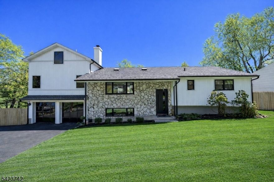 Taken down to the studs and meticulously redesigned in 2024, this custom home features sweeping views of Essex County's premier private golf course. Nestled on a quiet hillside street, 8 Rand Drive offers a newly constructed primary suite with 18-foot cathedral ceilings, dual walk-through closets, a 70-square-foot wet room bath with soaking tub, and its own dedicated HVAC system. A sliding glass wall in the main living area opens to a Trex deck, allowing the vistas to be enjoyed from both inside and out. Vaulted ceilings define the living room, which flows into an elegantly modern kitchen with an oversized quartz island, a Dacor refrigerator, and a spacious concealed pantry with prep sink. A wood-burning fireplace anchors the lower level, which opens seamlessly to the heated saltwater pool through a wall of glass bi-fold doors. Flanking the pool are a jacuzzi with gazebo and a stylish, custom-tiled outdoor kitchen with built-in grill. Additional features include wide-plank white oak flooring and sleek black-framed windows throughout, imported European light fixtures, and bespoke detailing tailored to each space.