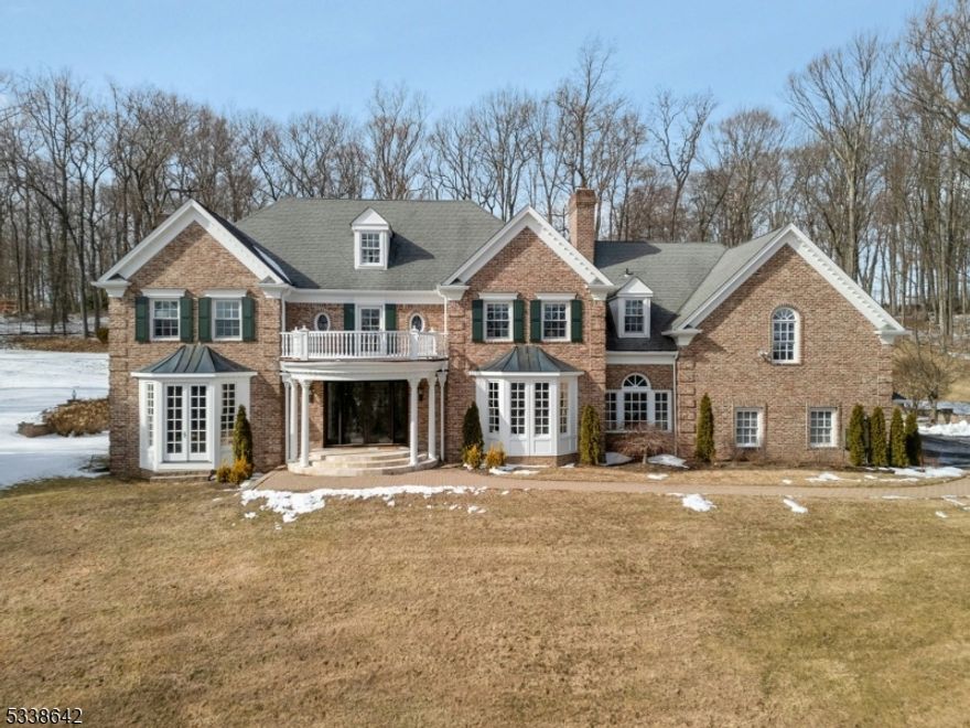 Situated on nearly 7 acres on prestigious Bernardsville Mountain, this majestic brick colonial offers an opportunity for extraordinary living both indoors & out. A private road winds through open fields & handsome stone gates on the approach to the home. Inside, a sunlit foyer introduces a floor plan that is perfectly suited for entertaining & daily living. The elegant dining room has a wood-burning fireplace & bay window. The formal living room features another bay window & wood-burning fireplace & leads to a spacious family room with wood-burning fireplace, pickled pine paneling & French doors opening to the patio. A magnificently renovated kitchen serves as the heart of the home & boasts quartzite counters, custom cabinetry, a coffered ceiling, expansive center island & French doors leading to the patio. Nearby, a mud room has 2 full-size wine refrigerators & a sunlit reading nook. Four generously sized bedrooms are found on the 2nd level, along with 3 full baths, a laundry room & large bonus room. The primary suite features gas fireplaces in both the bedroom & spa-like bathroom & a custom walk-in closet. The 3rd level offers the 5th bedroom & another full bath. The lower level includes a large rec room, powder room & utility & storage spaces. Outside, a paver patio overlooks a heated gunite pool with hot tub. Five acres are deer fenced. Sweeping views of Somerset hills & Manhattan beyond + proximity to town, train station & major highways make this home an ideal retreat!