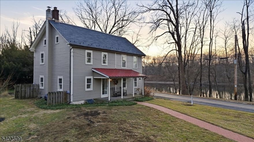 Built in 1836, this three-bedroom, one-and-a-half-bath colonial is set along one of the most private roads in Hunterdon County, directly on the Delaware River and within walking distance to the Riegelsville boat access. With river frontage at your doorstep, outdoor recreation is part of everyday life. Fish, kayak, tube, or walk down to the water and enjoy the changing seasons. Bald eagles are a familiar sight, often seen right from the front of the home. An expansive outdoor patio creates the perfect setting for gathering, dining, or simply taking in the river views and surrounding landscape. A one-car garage adds everyday convenience without taking away from the home's historic character. Inside, original wide-plank floors, hand-hewn beams, and period details reflect the home's early history while creating warm, comfortable living spaces. The main level offers functional gathering areas with an upgraded kitchen, while the three bedrooms provide quiet retreats at the end of the day. An oversized walk up attic can be finished or used for more storage. The home works equally well as a full-time residence or a second home for those looking to escape the pace of daily life without giving up accessibility. Private, riverfront, and rich in character, this is a rare opportunity to own a Delaware River property that balances history, outdoor living, and everyday comfort. If you love nature, privacy, and homes with a true sense of place, this property is worth experiencing in person.