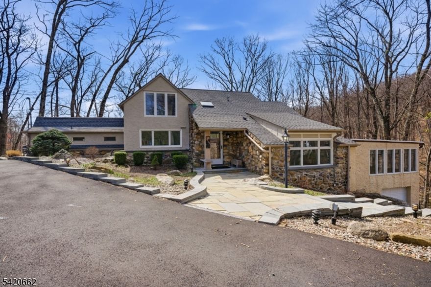 Nestled in the highly sought-after Lake Valhalla section of Montville, this one-of-a-kind Habberstad custom colonial blends timeless charm, rich history & exceptional privacy on 3.3 wooded acres backing to 44 acres of preserved open space. Offering 4 bedrooms & 2.5 baths, this expansive home is filled with character?beamed ceilings, custom woodwork, built-ins, a stunning wood-burning fireplace & hardwood floors throughout. The main level features formal living & dining rooms plus a spacious family room ideal for entertaining & everyday living. A 1st-floor primary suite with full bath & sitting area offers flexibility, while a den/home office adds versatility. The eat-in kitchen showcases shaker cabinetry, butcher block-style counters & classic black & white checkerboard flooring. Powder room & laundry complete the level. Upstairs offers 3 generously sized bedrooms, a sitting area & full bath. Enjoy multiple decks, including a new deck (2024), bluestone walkways, patio & mountain views surrounded by mature trees. Additional highlights: new roofs (2024 & 2026), new driveway (2025), new heat pump water heater (2024), dishwasher (2024), gas dryer (2023), fenced yard (2023), interior paint & blinds (2023). Circular driveway, garage, basement storage & shed. Minutes to Boonton Main Street, dining & commuter routes. Top-rated schools. A rare blend of privacy, updates & character. Northeastern facing front.