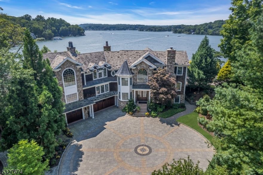 Luxury living offers over 600 ft waterfront with stunning sunset views. This custom-built lake home is designed to entertain! 3 living levels, an elevator, a double-wide boat house, patios, decks, docks, a gazebo, and a sandy bottom swimming area with easy access steps that lead to the lake. The grand entry welcomes you into the main living level with an open floor plan and sweeping views of the lake. New custom kitchen, stylish wood cabinetry, high-end stainless appliances, center island to enjoy casual meals opens to the dining & living rm offering a wood burning brick front fireplace and a new wet bar all with convenient access to the outdoor decking. There are two main-level bedrms with ensuite full baths and a bonus entertainment rm built to offer tremendous privacy for guests. The 2nd floor living begins with the primary suite overlooking the lake. A custom walk-in closet with built-in cabinetry. An all-new stunning ensuite bath with a soaking tub, free-standing shower, and a separate laundry rm. There is a private sitting area where you will enjoy a gas fireplace and opens into a stately office with a gas fireplace and access to an outdoor deck. The finished lower level lends to the 4th bedrm and a full bath or in-law suite. A bonus rm with access out onto the lakefront patio perfect for a fitness center or mud rm. The walk-out three-car finished garage offers additional plumbing and the new elevator to the main floor living and 5th bedrm opportunity. (3 bdrm septic)