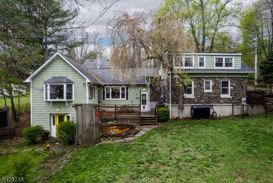 A storybook setting with modern day vibes.  From the babbling Brook to the stone fire place to the what seems like a Secret Garden patio, this home creates an environment like no other.  Upon entering, you'll fall in love with the warmth & character of the Parlor, with a wood burning fire place, a cleverly design Pocket Office tucked under the stairwell, the Powder Room with a chic wall mounted sink & the rustic original hardwood floors, grab a book & a cup of Jo, this is the perfect quiet spot.  Around the corner is an updated modern day kitchen with white Granite counters tops, striking blue cabinetry, added open shelving & tongue & groove ceiling that extends into the Dining area.  The Dining Room has a vaulted ceiling with exposed beams & tons of natural light. The Great Room is stunning with vaulted tongue & groove ceiling, skylights & a large picture window overlooking the yard & brook. This is a great entertaining spot! Tucked in the back is the spacious Primary retreat with a private Ensuite. The upper level offers 2 additional rooms each with their own appeal, one simple & timeless, the other enriched with warmth & character. Need more room? The Ground Level offers additional living space, currently a workshop, this room is ideal for a home office, gym, game room PLUS it has a private entrance!  The true gem of this home lies outdoors, with the pond, rock walls, gardens and of course the babbling Brook. Escape to the private patio & enjoy your enchanted haven.