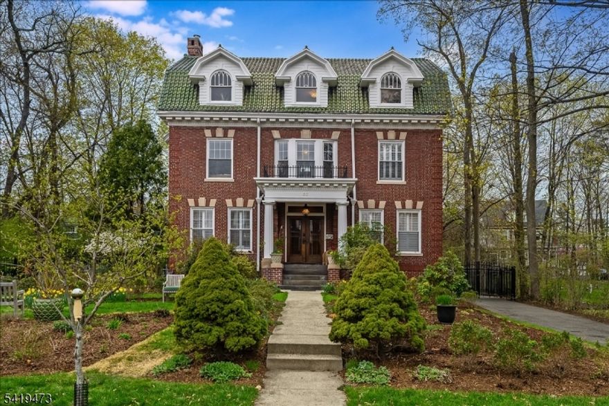 Nestled in the coveted Montrose neighborhood of South Orange, this stately Colonial blends timeless architectural detail with thoughtfully curated modern updates. From the moment you arrive, the home's elegant presence and classic charm set the tone for what awaits inside. A gracious double-door entry opens to a sun-drenched interior with original parquet floors & ribbon inlay, oversized windows, and exquisite custom millwork throughout. The coffered-ceiling living room is both grand and inviting, featuring a gas fireplace, and flows seamlessly into a bright sunroom overlooking the expansive, fenced backyard.  Designed for entertaining and everyday living, the spacious kitchen is a true centerpiece with an oversized island, six-burner range, double sinks, and abundant storage. Upstairs, the primary suite is a luxurious retreat with custom dressing room and a spa-like bath with handmade zellige tile, steam shower, heated floors and soaking tub. Two additional bedrooms and a Carrara marble full bath complete the second floor. The third level offers exceptional flexibility with three additional bedrooms, (one currently used as a movie screening room), plus great light, high ceilings, and extra storage.  Outside, enjoy a generous backyard, landscaped native gardens, and a rare 4-car garage with a lofted 2nd level offering exciting potential.  This is a truly special home where historic elegance and modern comfort come together in the commuter friendly town of South Orange.