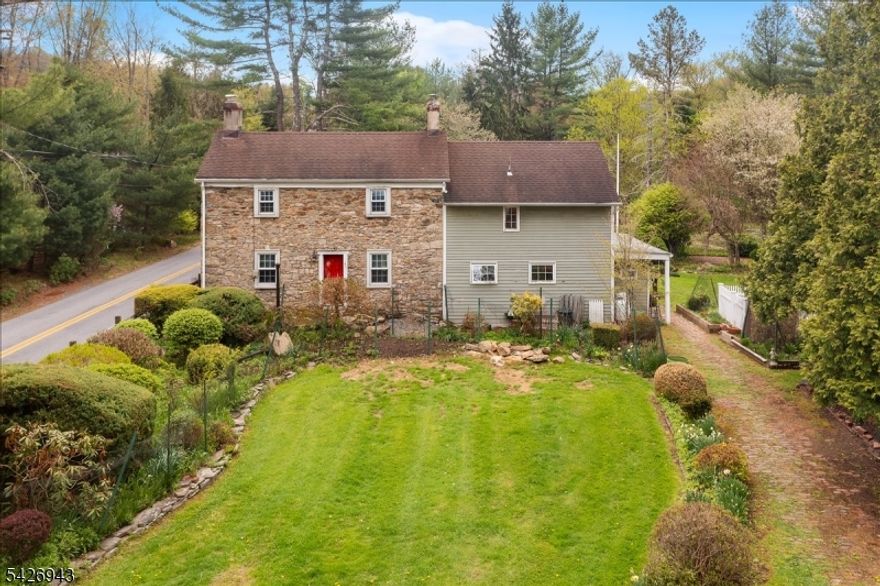 This 1780s stone colonial is situated on 3.64 acres, offering a serene rural setting in sought after Lebanon Twp. This home blends historic character with practical living spaces. Original stonework, wide board floors, beamed ceilings are just some of the period details. The main floor includes a light-filled sunroom with wall to wall windows & views of the pond, a spacious living room with a stone fireplace w/ wood-burning stove, and a kitchen with slate flooring and beamed ceilings that is open to the dining area. A mudroom/laundry area & full bath complete this level. The second floor consists of a primary bedroom with an adjacent versatile room suitable for a fabulous walk-in closet or imagine a new primary bathroom. Walk through to the office area, and there is a full bathroom, and a second large bedroom with ample closet space. Additional features include a Jersey winder staircase, a spiral staircase to the upper hallway, and a basement and attic for storage. The property also includes a large outbuilding ideal for a 3 car garage, workshop, or for your hobbies. The grounds are comprised of open lawn, wooded boundaries, mature trees, lush landscape and a pond. Tons of potential here, this home won't last long. Conveniently located near Route 31, Route 78, and train or bus to NYC, this home provides easy access to excellent schools, shopping, Ken Lockwood Gorge, and Spruce Run Reservoir.
