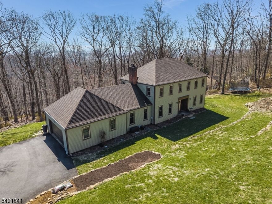 Nestled at the end of a beautiful driveway private driveway in Bethlehem Twp, Hunterdon County, this stunning 4-bedroom, 2.1-bath Colonial delivers the perfect blend of privacy, character, and breathtaking natural beauty. Sweeping panoramic views of a glistening reservoir and rolling mountain ridgeline greet you from the elevated lot, a backdrop that simply cannot be replicated. Inside, a beautiful mix of narrow & wide-plank hardwood floors flow throughout the main level, complemented by exposed beam ceilings, classic wood wainscoting, and a dramatic floor-to-ceiling brick fireplace with wood-burning insert that anchors the generous family room. The well-appointed kitchen features solid knotty pine cabinetry, a double wall oven, stainless French door refrigerator, and a sun-filled eat-in area with 2 points of access on either side of the kitchen to the expansive deck. Formal dining room, gracious foyer with open staircase, and a convenient first-floor laundry with mud room entry complete the main level. Upstairs, the primary suite offers a private bath and walk-in closet, while three additional bedrooms with ceiling fans share an updated hall bath with granite vanity. The finished walk-out lower level is ready for a home gym, media room, or recreation space. Outside, the multi-level hand-laid stone terracing and private wooded yard create an entertainer's dream. Covered front entry porch, oversized 2-car garage. Minutes to Rt. 78, Rt. 22, and Flemington dining and shopping!!!