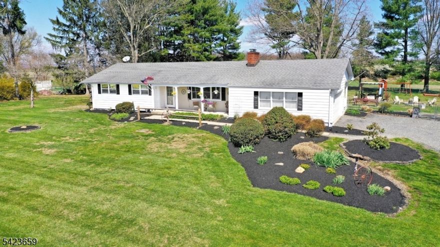 Welcome home to this charming 3-bedroom, 2-bath ranch set on 1.56 acres with beautiful farmland views. Surrounded by meticulously maintained landscaping, this single-floor home offers a spacious layout highlighted by a large living room with a rustic stone fireplace and beamed ceiling. The home offers three spacious bedrooms, including a primary bedroom with a walk-in closet. The hardwood floors have been recently refinished, and the entire home has been freshly painted. Additional features include central A/C, full basement with a recreation area plus a wood stove and bar, ideal for entertaining or flexible use along with a separate section for laundry, heating system, and ample storage. Bilko doors provide convenient exterior access. Enjoy indoor-outdoor living with a welcoming front porch and a covered back porch complete with an outdoor TV. The expansive and fully fenced backyard features a fire pit and a wonderful open setting for gatherings, recreation, or simply relaxing. Two-car garage with built-in shelves and cabinets, expanded driveway parking area, and large backyard storage shed. Portable generator included. Located in a Blue-Ribbon school district, this home offers a peaceful rural feel while being minutes from dining, shopping, and entertainment in the historic river towns of Stockton, Lambertville, and New Hope. If you've been searching for space, and a true country feel without sacrificing convenience, don't miss this one!