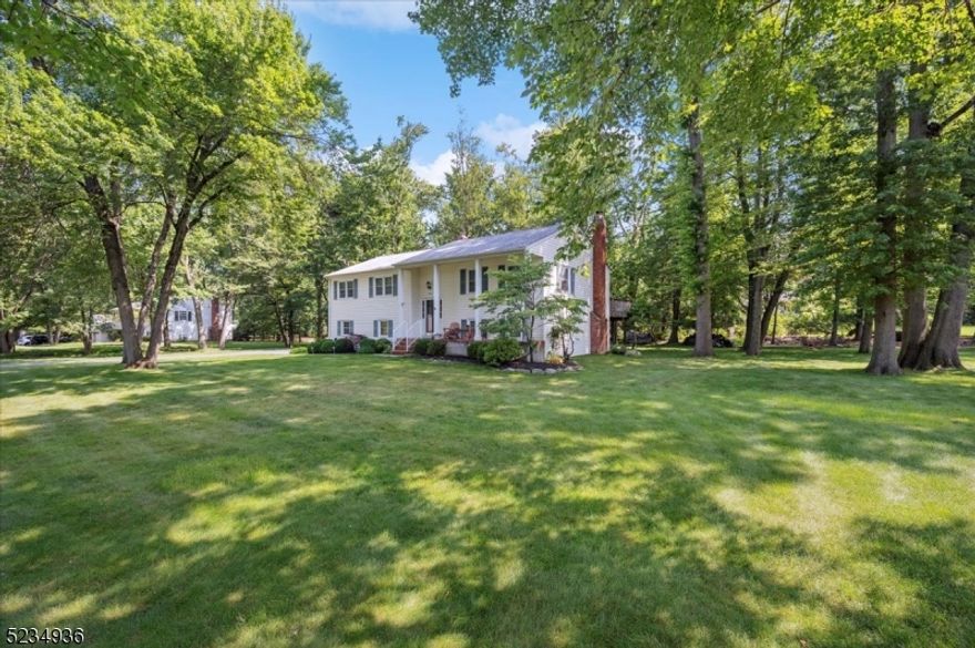 Immaculate Home with Classic Details & Tranquil Location! Beautifully updated 4Bd, 2.5 Bth Bi-level home on landscaped 1/2-acre corner property at the end of a street surrounded by trees for a peaceful setting.  Unbeatable location close to shopping, dining and block away from top rated school as well as quick access to I-80 + I-287 for easy commutes. A graceful front porch and entry usher you up to a bright, airy main level with gleaming hardwood floors and ample natural light. An open living and dining room with chair rail detail leads to a gorgeous kitchen with crisp white cabinets with pull out shelves, granite counters, recessed lighting, peninsula with seating, and stainless-steel appliances including dual wall ovens. Sliding glass doors off the kitchen and dining room provide access to a sprawling Trex deck overlooking the backyard with plenty of space for cookouts, relaxing, gardening or playing games. Wood floors continue down the hall to 3 bedrooms with ceiling fans and lots of closet space, with the primary offering an en-suite bath. A full bath with wide stone-topped vanity and tub/shower is in the hall. The lower level has additional living space, boasting a cozy family room with outside entry and brick fireplace flanked by built-in shelving, plus a 4th bedroom with a huge closet, a laundry room with adjoining powder room, and access to the attached 2-car garage. This well-maintained home is move-in ready, just waiting for you to unpack and enjoy!