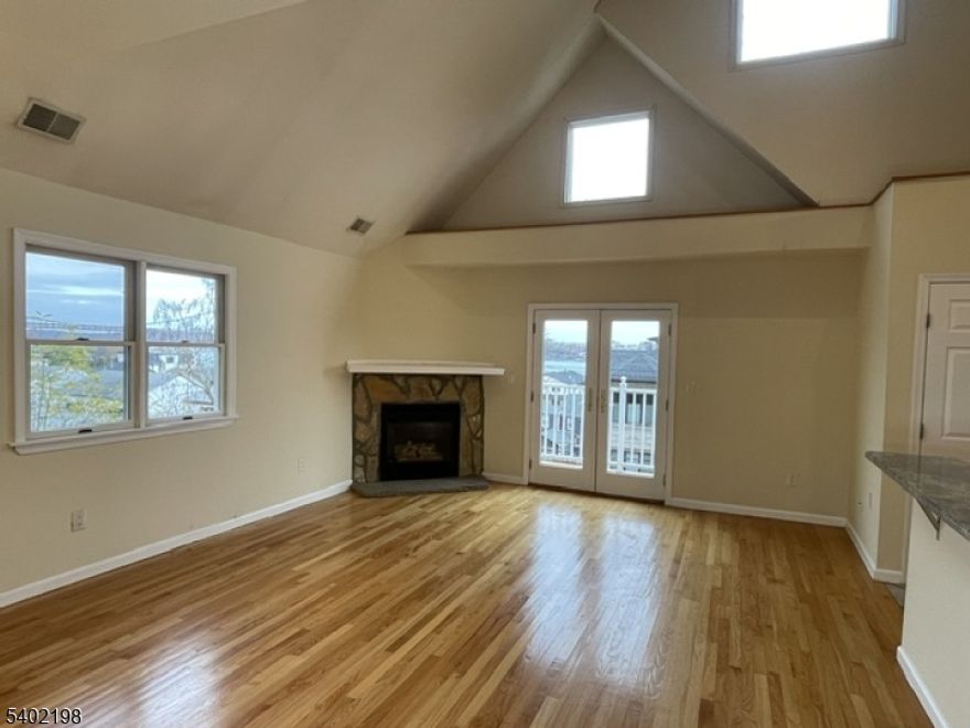 Beautifully designed open-concept kitchen and living room featuring vaulted ceilings and a cozy fireplace. Enjoy a small balcony with stunning Hudson River views. The primary bedroom offers a walk-in closet and private bath, while the second bedroom provides direct access to the backyard. A spacious open loft serves as a third bedroom or flexible living space. Located in the heart of Edgewater, this home boasts gleaming hardwood floors, abundant closet space, and includes both a garage parking space and a carport. In unit washer & dryer. Conveniently close to fine dining, shopping, and easy transit options to NYC. An exceptional home in a prime location!  Owner has a NJ real estate license.