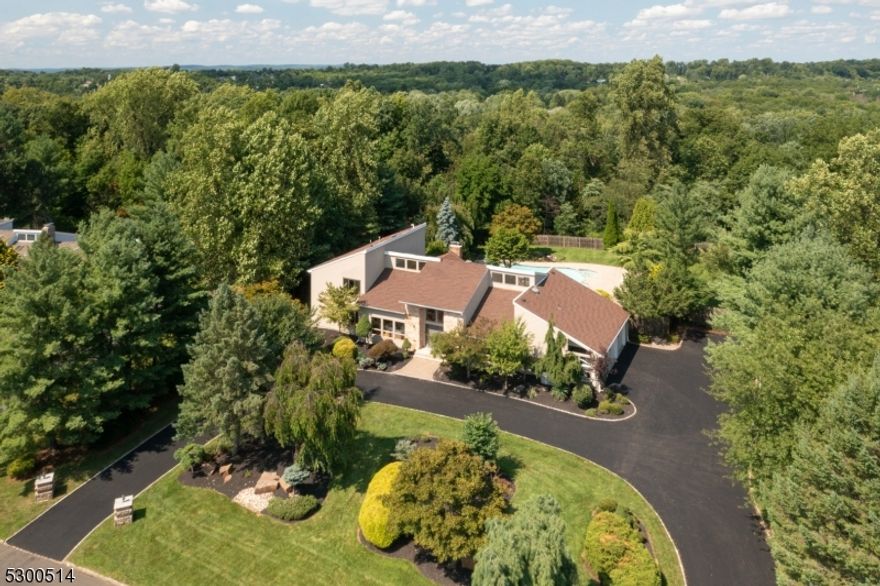 Exceptional Custom Contemporary home, elegantly situated on over an acre of a level lot, nestled in the hills of Warren.  This property is ready for entertaining with its large open space floor plan, extensive circular driveway, a magnificent inground pool, expansive wrap around porch, and an oversized rec/bar room with vaulted ceilings, skylights, and sliding doors that lead directly to the outdoor paradise.  Natural sunlight floods all areas of the home thanks to picture windows and tall ceilings throughout.  A newly renovated kitchen is a chef's dream, and offers custom cabinetry, new appliances, and an eat in kitchen space.  The main level primary bedroom retreat is the perfect place to unwind with an adjacent sitting room/office space, walkin cedar closet, and a spa like en suite with a dual sink vanity, soaker tub, and stand up shower.  A sunken family room is highlighted by vaulted ceilings, and a stately stone wood burning fireplace.  The fully finished lower level presents with a full bathroom, and plenty of space for a gym, movie theater, hobbies, and recreation.  The backyard oasis is highlighted by a dreamlike inground pool, surrounded by mature landscaping that provides privacy, beauty and serenity.  Located close to The Pingry School, in an excellent school district, and within close proximity to County parks, and highways 78/22/287/202/206.