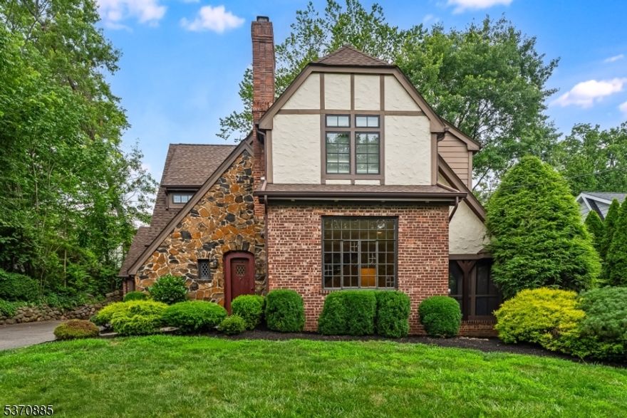Enchanting Knollwood Tudor, with its brick, stone & stucco exterior, features a dramatic living room with cathedral beamed ceilings, stone wood-burning fireplace, and a vintage leaded glass window. The bright dining room leads to an updated gourmet eat-in kitchen equipped w/Wolf 6-burner gas range, SubZero refrigerator, granite counters w/center island & breakfast room seating, all open to a cozy family room. A charming screened-in stone porch and an English paver patio overlook the garden and play area. The first floor also includes a foyer w/walk-in closet and a powder room. On the second level, the glamorous primary bedroom boasts a vaulted ceiling, multiple closets, and an updated en suite bath with walk-in shower, double vanity with granite counters, & a pocket door. Three additional spacious bedrooms share a modern full bath w/double vanity. The finished lower level includes a large rec room, office/guest bedroom, full bath, laundry & utility room. Recent enhancements include fully remodeled lower level, whole-house generator, water softener/filter & EV charger. Set in the highly desirable Hartshorn Elementary School District, this home is just a block to Millburn Middle School, four blocks to Millburn High School, and steps to downtown Millburn, Paper Mill Playhouse, and direct train service to NYC. Knollwood is renowned for its Halloween parade and local block parties, combining suburban tranquility with convenient access to parks, shops, and houses of worship.