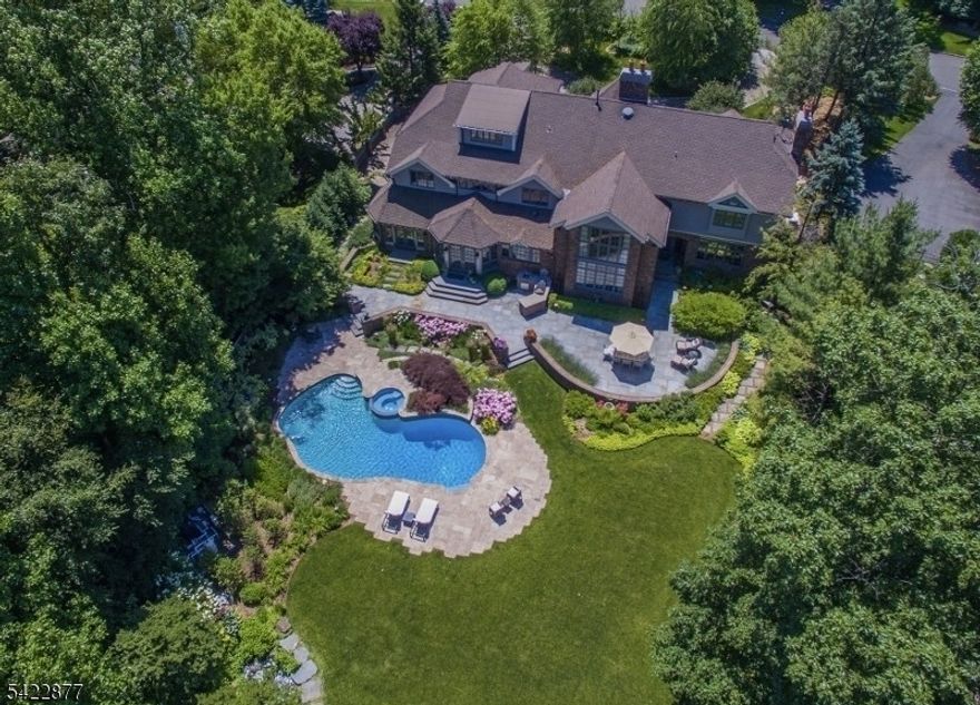 Live like you are on vacation every day in this modern North Caldwell estate, where bold design meets resort-style luxury. A dramatic marble entry and sweeping staircase set the tone, complemented by soaring ceilings, sleek millwork, and wide plank hardwood floors. Built with steel beam construction and surrounded by lush landscaping, water features, and curated gardens, the home offers exceptional privacy and tranquility. The Canterbury-style chef's kitchen anchors the main level with high-end appliances and timeless finishes, opening to a sun-filled glass solarium, perfect for year-round living. Upstairs, the primary suite delivers a true retreat with a spa bath, oversized shower, and soaking tub, while all additional bedrooms are spacious and ensuite.The finished lower level transforms the home into a private club, featuring a mahogany bar, climate-controlled wine cellar, FULL SWING GOLF PRO simulator, fitness room, projection theater, and lounge spaces designed for entertaining.