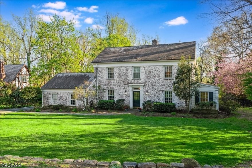 Nestled in the prestigious Spring Brook neighborhood, this timeless 1930s Colonial blends historic charm with modern luxury. Set on a sought-after street, the stately brick home showcases exceptional craftsmanship, a classic slate roof, and professionally designed hardscaping for enduring curb appeal.Designed for elegant living and effortless entertaining, the home offers refined yet inviting spaces. The gourmet kitchen features a Viking six-burner range with pot filler, custom cabinetry, and a granite island with seating. It flows seamlessly into a formal dining room with gleaming hardwood floors and a gracious living room with a fireplace. A private office provides a quiet retreat, while the sun-filled, sunken family room with its own fireplace opens through French doors to an expansive bluestone patio, ideal for indoor-outdoor living.The primary suite is a true sanctuary with 11-foot ceilings, a spa-inspired bath, walk-in closet, and Juliette balcony. Three additional bedrooms and updated baths offer comfort and style, complemented by detailed moldings and hardwood floors throughout.The finished walkout lower level adds versatility with a recreation area, second family room, and powder room. Set on .44 manicured acres with tiered lawn and mature evergreens, this move-in ready home offers privacy and timeless appeal.