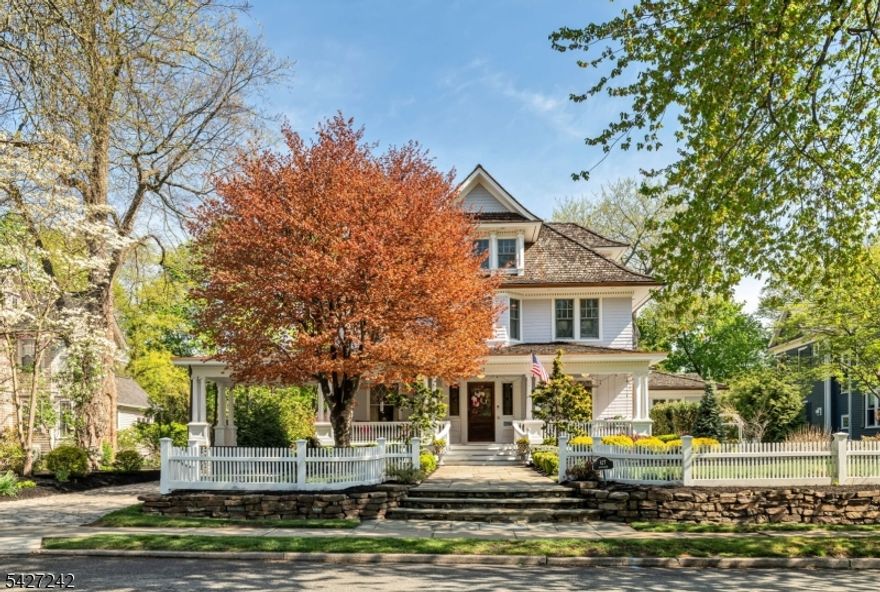 Set on a breathtaking 280-ft landscaped property along prestigious Spring Avenue, this exceptional 5-bedroom, 4.5-bath Colonial is surrounded by some of Ridgewood's most iconic homes, offering a rare blend of timeless beauty and modern luxury. A graceful curved white picket fence, port cochere, and cedar roof create outstanding curb appeal, while the covered front porch invites slow mornings and peaceful evenings. The backyard is a private retreat with a rear deck, greenhouse, sport court, vegetable garden, fenced lawn, and a 3-car garage with a finished loft/studio. Inside, rich original woodwork, a dramatic 3-story staircase, leaded glass French doors, stained glass windows, and coffered ceilings add warmth and character. The newly renovated custom kitchen features a 9-foot island, top-tier appliances, a cozy fireplace, and oversized sun-filled picture windows that bring the outdoors in. Formal living and dining rooms, a private office, and an updated family room with walls of windows plus an adjoining mudroom offer both elegance and ease. Upstairs, the serene primary suite with spa-like bath is complemented by four additional bedrooms and a laundry room. The lower level adds a versatile family room, guest suite, new full bath, second laundry, hobby room, and ample storage. Ideally located near top-rated schools, downtown Ridgewood, and NYC transportation, this is a truly special home ready to be enjoyed for years to come.