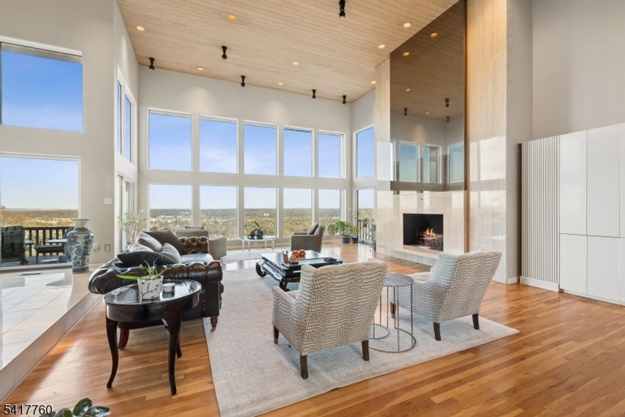 Perched majestically atop the Watchung Hills in a remarkably quiet and serene neighborhood, this California-inspired masterpiece offers a rare fusion of architectural brilliance and breathtaking, panoramic vistas. Floor-to-ceiling glass and soaring cathedral ceilings invite the Manhattan skyline and the rolling New Jersey landscape into every room, creating an ever-changing gallery of light and color. The home's versatile layout features a luxurious first-floor master bedroom suite alongside a sophisticated second-floor suite, both thoughtfully refined with a master bath shower and powder room newly renovated in 2024. From the chef's kitchen and dramatic open-concept living spaces to the walk-out lower level with its entertainment space and sauna, every inch is designed for an elevated lifestyle. Outside, a stately circular driveway lined with cherry blossoms leads to a 3-car garage and a wraparound deck that feels suspended above the world all just 45 minutes from Manhattan and moments from top-rated schools.