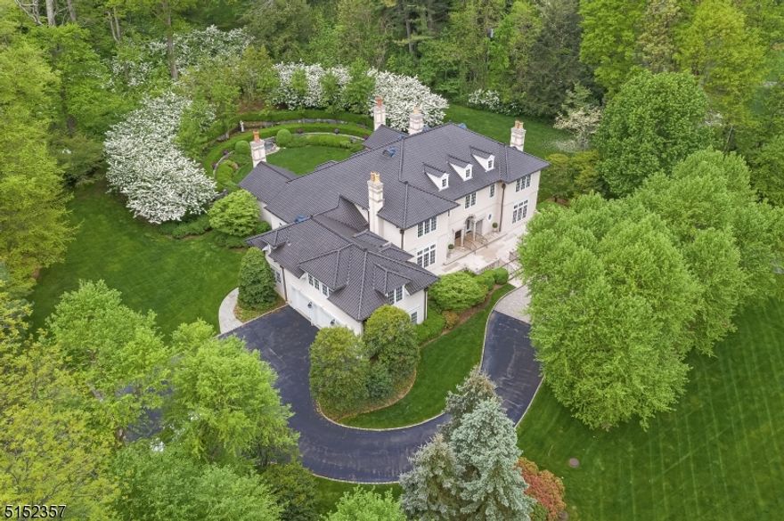 At the end of a meandering private drive, off a country road in New Vernon, NJ, a rare offering awaits. Perched above surrounding properties this estate sits majestically on 3.48 impeccable acres. The 6 bedrm, 7.2 bath stucco & limestone home offers every appointment for a well-lived life; creating fantastic living and entertaining spaces while maintaining an intimate and cozy feel. Enter the breathtaking foyer. Two stories high, it is graced with marble floors, a coffered ceiling with cove lighting and a sweeping curved staircase setting the tone for this remarkable residence. Three primary rooms are accessed from the foyer: on one side is the formal dining rm with in-laid wood flooring and paneled wainscoting. Opposite is a wood paneled library with a wet bar & gas fireplace. The formal living rm boasts two-story ceilings, gas fireplace, and an impressive built-in mirror. The 1st floor primary suite offers two walk-in closets, en-suite full bath & sitting rm. The large kitchen with custom cabinetry, granite countertops & marble floors opens to the family rm with coffered ceilings & gas fireplace. A mudrm, butlers pantry, laundry rm & two powder rms complete this level. Upstairs finds 4 en-suite bedrooms centered by an open vestibule. A separate guest apartment with kitchen, living rm & full bath is tucked away on the 2nd level. The finished lower level includes a rec room, billiardsrm, gym, sewing rm, wine cellar & full bath. Exquisite gardens and mature grounds surround.