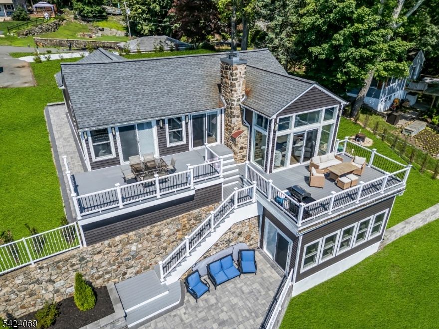 EXPANSIVE LAKEFRONT VIEWS!! Elegantly perched high above the coveted Wildwood Shores community, this 2024 FULLY RENOVATED 3-bedroom, 2-bath home delivers panoramic Main Lake views of Lake Hopatcong. Wake up to sunrises that paint the water in gold from one of three maintenance-free decks, each offering its own breathtaking vantage point. Inside, an open-concept layout with soaring ceilings and a dramatic wall of windows floods the living space with natural light, centered around a rustic fieldstone wood-burning fireplace - the perfect balance of cozy and contemporary. The property includes THREE LOTS sold as one. The oversized three-car detached garage offers ample storage for lake toys, while dual driveways and parking for up to eight cars make entertaining a breeze. A walkout basement with bonus room enjoys its own lake view and endless potential - gym, office, guest suite, or creative studio. Front access from 31Wildwood Shores Drive offers level entry, while the rear 12 Bass Rock Road access leads to both the home's upper decks and the large level front yard and garage. Enjoy the amenities of Wildwood Shores... walk to the four private lakefront access points (three with sandy beaches), fishing docks, clubhouse, and optional boat or wave runner docking (fee/seniority based). A private, HOA-protected enclave with NO short-term rentals, it's the ideal blend of peace, community, and recreation. Close to shopping, restaurants and NYC transportation.