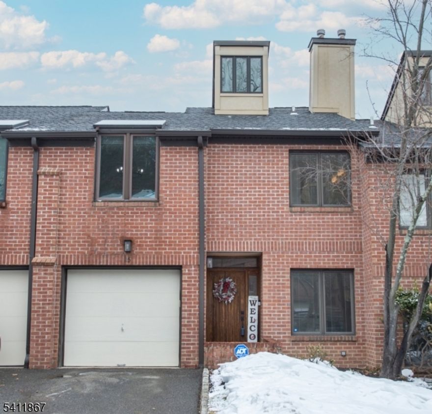 Step into this luxurious, fully renovated townhome in the highly sought-after Stepping Ridge community of North Caldwell. This ground-level entry unit has been meticulously updated with no detail overlooked. Upon entry, you're welcomed by a spacious foyer that leads to an expansive sunken formal living room featuring vaulted ceilings, a gas fireplace, sliders to a private deck, and brand-new LVT flooring. The beautifully renovated kitchen offers stainless steel appliances, a tiled backsplash, abundant cabinetry, and a dedicated coffee/beverage bar complete with a beverage refrigerator. The kitchen flows seamlessly into a formal dining room enhanced by custom woodwork and detailed moldings. A convenient powder room completes the first floor. Upstairs, you'll find a cozy reading nook, a generously sized primary suite with two closets, and a fully renovated en-suite bath showcasing double sinks, a tiled walk-in shower, and a soaking tub. The second bedroom is also spacious and is served by a newer hallway bath. The walkout lower level includes a large third bedroom (currently used as a family room) with sliders to a patio overlooking a peaceful wooded and grassy setting. This level also offers ample closet space, a laundry/utility room, and additional storage. Additional features include a one-car built-in garage equipped with an electric vehicle charger. Don't miss the opportunity to view this exceptional unit - it won't last long!