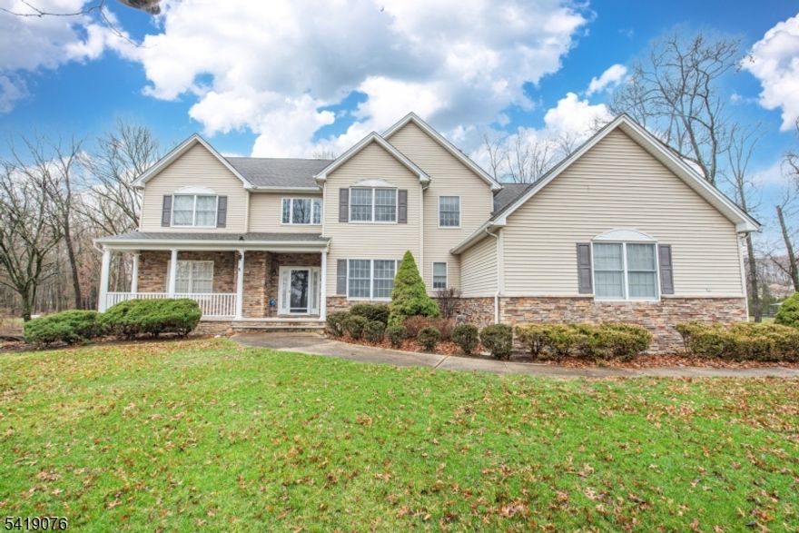 Impressive 5 bedroom, 2.5 bath Colonial with a welcoming front porch, 3-car attached garage, and beautifully landscaped property. Step into a grand foyer with soaring ceilings, hardwood floors, and a stunning chandelier. The main level offers a versatile office/bedroom, formal dining room, and an open layout ideal for entertaining. The spacious kitchen features granite countertops, custom wood cabinetry, center island, breakfast bar, pantry, and high-end stainless steel appliances including a double oven. A custom wet bar with wine cooler adds a perfect touch for hosting. The family room showcases cathedral ceilings, a dramatic Palladian window, and a double-sided fireplace shared with a cozy living space on the other side. Sliders lead to a large deck overlooking a private, fenced backyard with wooded views. Upstairs, the primary suite offers high ceilings, generous space, and an en-suite bath with double vanity, stall shower, and jacuzzi tub. Additional bedrooms are well-sized with ample closet space, and a full bath with double vanity completes the second level. A large partially finished basement provides endless possibilities for recreation, storage, or expansion. Additional features include central air, forced hot air, public utilities, and a spacious driveway. Beautiful home. WON'T LAST!