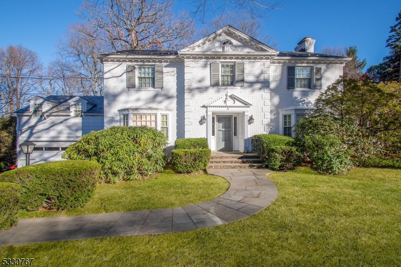 Stately 4 bedroom 4.2-bath center hall Colonial home boasts beautiful curb appeal, set on 0.5 acre property in Summit's prime Woodland Park neighborhoods. Elegant foyer with graceful staircase introduces a front-to back living room with central wood-burning fireplace and a formal dining room with picture window and built-in china cabinet. Versatile sunroom/playroom/home office with generous windows on three sides, access a bluestone patio surrounded by privacy bushes and deep rear yard beyond. A den/family room features a hidden wet bar with sink, ice maker, counter and cabinetry for entertaining. The kitchen w/breakfast area includes laundry hook-ups and a nearby back staircase to a private spacious second-floor home office or possible guest quarters with ensuite full bath. An open second-floor hallway leads to 4 bedrooms, two of which are ensuite with adjoining baths; 2 bedrooms are served by a full hall bath. Spacious primary bedroom has two double closets and adjoining primary bath w/oversized shower. Pull-down stairs to attic storage located in the hallway. Expansive finished lower level features a recreation room with built-in wetbar and counter seating, play and exercise areas; a half bath; walk-in closet; large storage room with shelving and utility room; access to two car garage. Mechanical systems include central air conditioning, water softener and house generator. Sold in As-is condition, this house presents an excellent opportunity for the creative homebuyer!