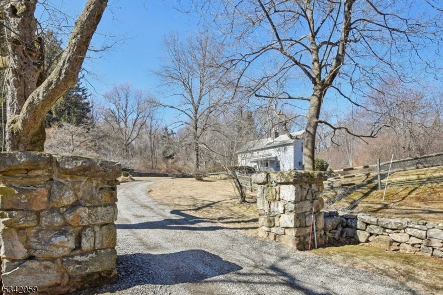 This beautifully renovated and expanded carriage house, nestled on over 5 acres of lush, private land, strikes the perfect balance between tranquility and convenience. Just 1 mile from vibrant downtown Bernardsville and the train station, this home offers easy access to all the amenities you need while maintaining the peace and privacy of a country retreat. The spacious, thoughtfully designed layout blends historic charm with modern upgrades. The first floor features a guest bedroom with an en suite bath, providing a comfortable and private space for visitors. Additionally, a well-appointed home office offers a quiet, productive environment. The large terrace seamlessly connects the indoor living spaces to the outdoors. Step outside to enjoy the custom PebbleTec pool, surrounded by beautifully landscaped grounds, with a tranquil pond enhancing the peaceful ambiance of the property. Inside, the open-concept living area is ideal for hosting guests and entertaining. The second floor includes four spacious bedrooms, including a large primary suite with an en suite bath. A bonus loft area on the third level offers endless possibilities perfect for a home office, play area, or additional living space. The property also features a detached 2-car garage, complete with a climate-controlled gym and game room, offering even more space for relaxation and recreation. With its perfect combination of luxury, location, and functionality, this property is truly one-of-a-kind.